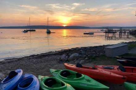 Kayaks on beach at sunset.